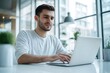 © kitipol - High-resolution brightly lit photorealistic candid photograph of a young marketer in casual attire, working on his laptop in a bright, modern office. The photograph is styled like a high-end