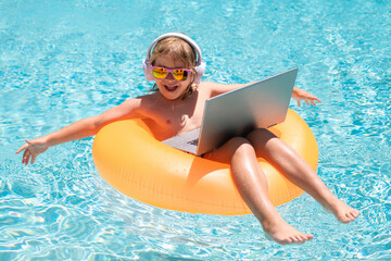 Wall Mural - Child with laptop in swimming pool in summer day. Summer business and online technology.