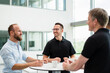 © Westend61 - Group of businessman having informal meeting standing in office hall with cups of coffee