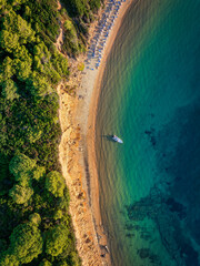 Wall Mural - aerial overhead sunset view of mantraki beach with emerald sea and lush pine tree forrest at the isl