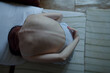 © Westend61 - Sad young woman bending over on bed at home