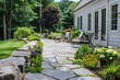 © JIALU - Charming backyard patio with stone walkway and seating area surrounded by greenery in a New England home garden.