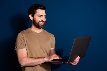 Canvas Print - Photo of mature age senior it specialist programmer brunet man with laptop working remote isolated on dark blue color background