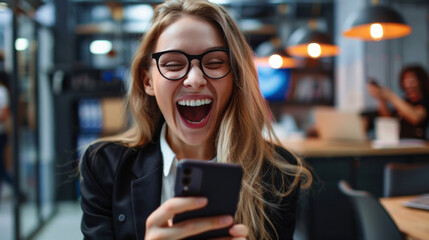 A young office worker holds a phone and smiles happily after receiving a large commission for her work.