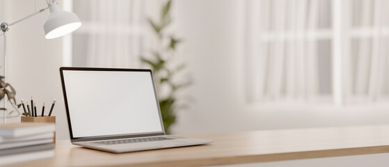 Wall Mural - A laptop computer with a white-screen mockup and decor on a wooden tabletop in a bright room.