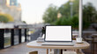 © bongkarn - A laptop computer with a white-screen mockup on a table on a coffee shop outdoor terrace or balcony.