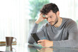 © Antonioguillem - Worried man checking cell phone at home