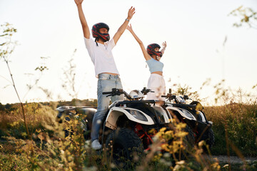 Hands raised up. Man and woman are on ATV outdoors