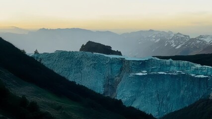 Sticker - Capturing a golden sunset on a mountain with a glacier and snow capped peaks in the background, showcasing nature's serene beauty and icy wonders