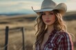 © Kenny - Young Woman in Cowboy Hat and Plaid Shirt in Rural Landscape at Sunset