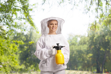 Wall Mural - Young female bee keeper in a uniform holding a spraying bottle