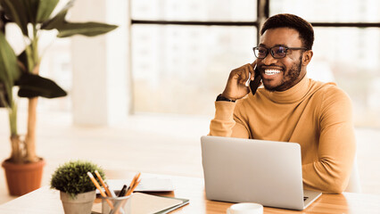 Poster - Communication Concept. Happy afro man talking on mobile phone in modern office. Panorama with copy space