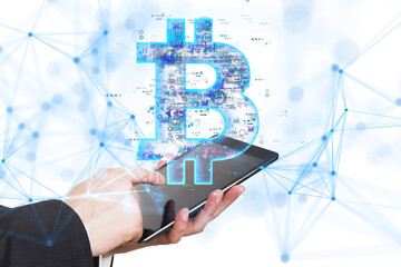 Poster - Hands holding a tablet with a digital Bitcoin symbol hologram above it, on a white background. Concept of cryptocurrency and digital finance