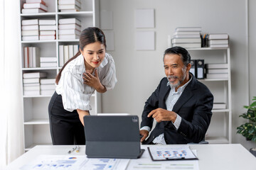 Wall Mural - A woman and a man are sitting at a desk with a laptop in front of them