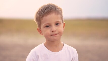 the boy looks into the camera. happy family kid dream concept. close-up of a child's face. the boy looks carefully. son in nature portrait. the child observes what is happening around him lifestyle