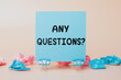 © Red Cristal - Sticky Note with 'Any Questions?' Written on It, Concept for Q&A Sessions, Inquiries, Customer Support, or Classroom Discussions. Blue Note on a Neutral Background