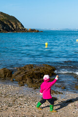 Child at sea playing with shells, sand and water