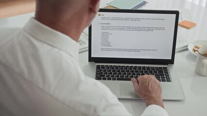 Wall Mural - Over the shoulder view of male entrepreneur sending email to business partner while sitting in front of laptop at office