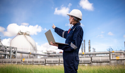 Engineers wearing safety gear, including hard hats examining survey a tablet standing industrial facility gas task or oil refinery engaged in a job requires high safety standards concept.