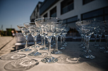 Empty wine glasses on a table in backyard. Table with empty wine glasses at a summer wedding. Festive wedding concept. Side view.