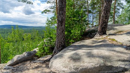 Small Devils rock, Devil's Hillfort complex on sunny summer day. Iset Park, Iset village, Sverdlovsk region, Russia. Hiking. Pine trees on rock