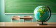 © Udomner - Minimalist green globe on a tidy teacher's desk, highlighting global learning as school resumes after summer, global learning