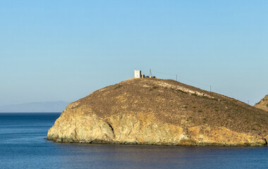 Wall Mural - Greece, Seascape at Andros island Greece. Stone wall   lighthouse up on the hilll