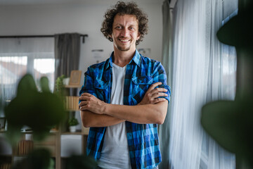 Wall Mural - portrait of adult man stand with arm crossed and smile at home