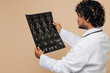© ViDi Studio - Young doctor man he wearing white medical gown suit work in hospital clinic hold x-ray radiographic image ct scan head brain mri isolated on plain beige background studio. Healthcare medicine concept.