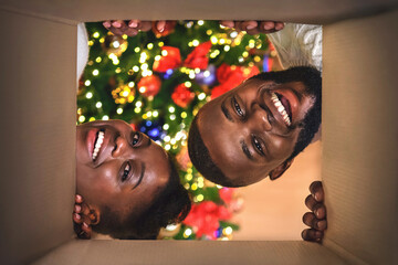 Magic moments. Excited African american couple opening Christmas present at home, view from inside of box.