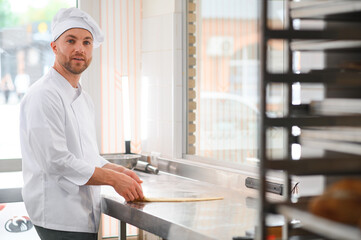 Baker kneading dough in a bakehouse or bakery