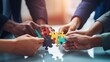 © kinara art design - A group of hands assembling colorful puzzle pieces on a table, symbolizing teamwork.