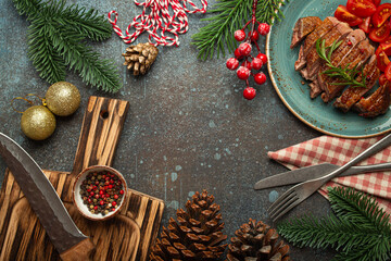 Wall Mural - Festive Christmas dinner boarder background with space for text with roasted duck breast fillet with golden crispy skin and tomato salad, Xmas decorations with fir tree, cones, red berries..