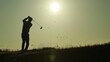 © buraratn - A golf silhouette against a bright sky, finishing a powerful swing.