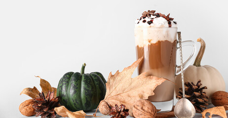 Wall Mural - Glass cup of tasty pumpkin latte with star anise and walnuts on white background