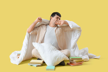 Sticker - Sleepy young man with blanket and books on yellow background