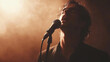 © Steven - Male singer passionately performing on stage with a microphone, backlit by warm, dramatic lighting creating a smoky atmosphere.