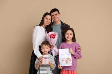 Sticker - Couple and children greeting their mother with Mothers Day with bouquet of flowers, drawing and gift near beige wall