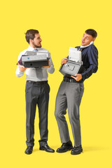 Sticker - Shocked young men with safe box and folders talking by phone on yellow background