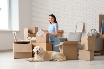 Poster - Young happy woman and cute Labrador dog with boxes on moving day at home