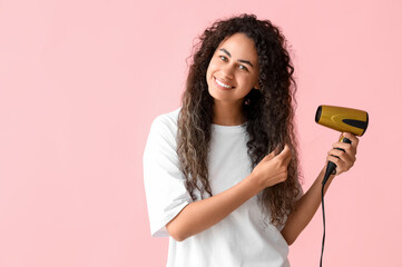 Canvas Print - Beautiful young happy African-American woman blow drying her healthy curly hair on pink background