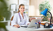 © JackF - Young female doctor sitting at desk in office and using laptop.