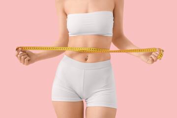 Poster - Beautiful young woman with measure tape on pink background, closeup. Weight loss concept