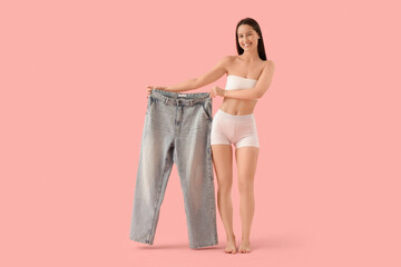 Poster - Beautiful young happy woman with plus size jeans on pink background. Weight loss concept