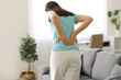 © Pixel-Shot - Young woman suffering from back pain at home