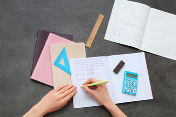 Wall Mural - Woman writing math formulas in copybook on dark background