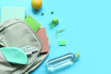 Wall Mural - Modern school backpack with different stationery supplies, bottle of water and apple on blue background