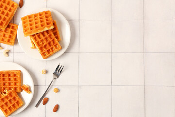 Wall Mural - Plates with tasty Belgian waffles and different nuts on white tile background