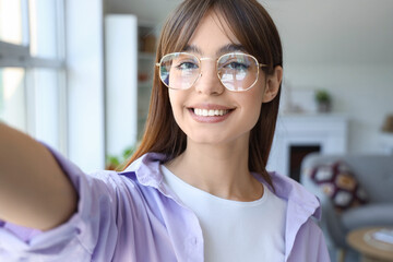 Canvas Print - Young woman in eyeglasses taking selfie at home, closeup