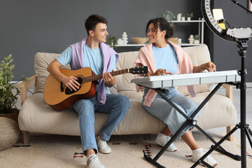 Canvas Print - Couple of bloggers with guitar and synthesizer recording video at home